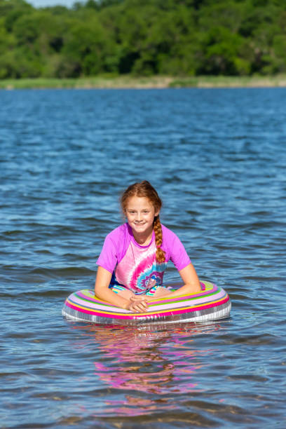 девушка, плавающая на озере в swim ring внутренний метро - inner tube swimming lake water стоковые фото и изображения