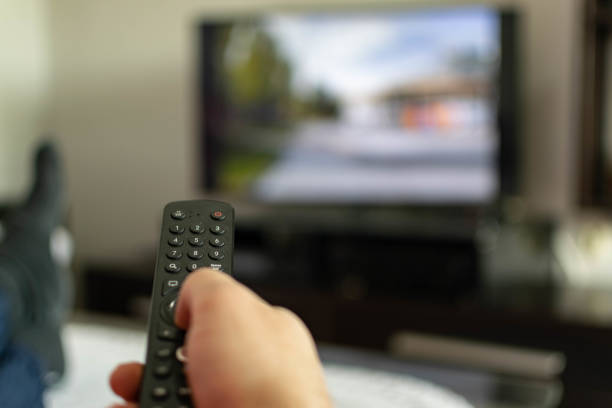 istock Using remote control, watching TV or opening apps on the smart TV, close up on the remote, blurred screen in the background. 1322493008