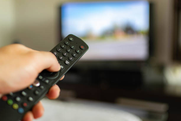 istock Using remote control, watching TV or opening apps on the smart TV, close up on the remote, blurred screen in the background. 1322493009