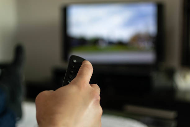 istock Using remote control, watching TV or opening apps on the smart TV, close up on the remote, blurred screen in the background. 1322493014