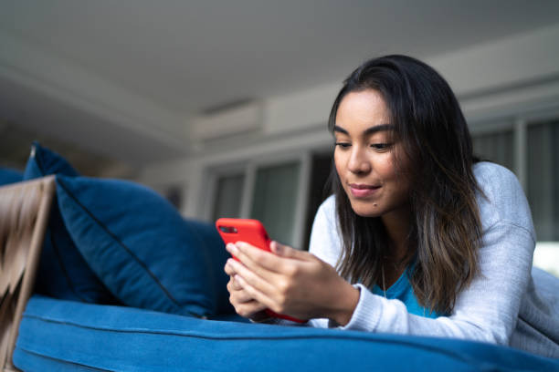 istock Happy young woman using smartphone at home 1322493093