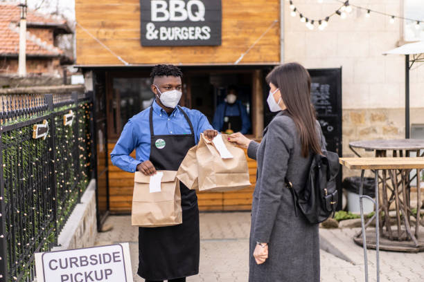 istock Waitstaff delivering take-out food from the curbside pickup area 1322493331