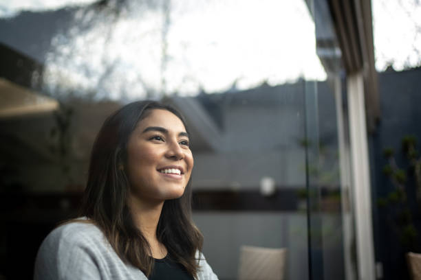 mujer joven contemplando en casa - esperar fotografías e imágenes de stock