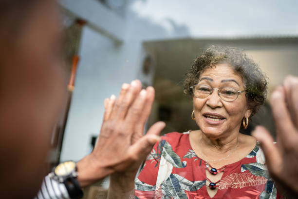 istock Senior couple separated greeting through the window at home 1322494119