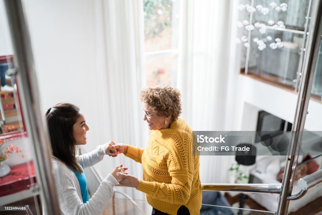 Nurse supporting senior patient walking or moving up the stairs at home Parkinson's Disease Stock Photo