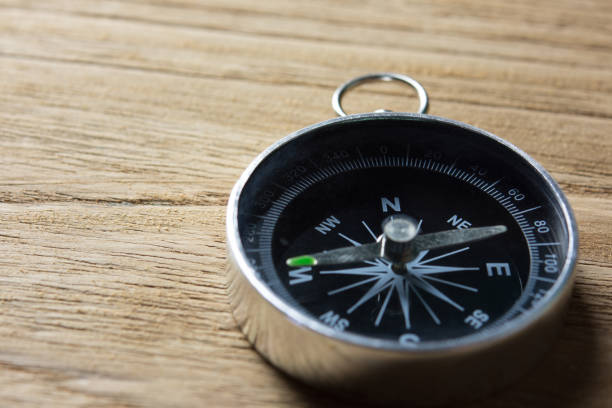 istock Close-up of magnetic compass on wooden table. 1322497181