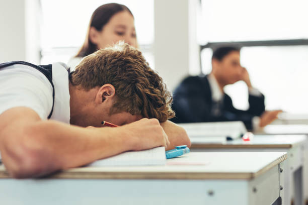 studente lice scolastico annoiato che dorme sulla scrivania della classe - sleeping high school desk education foto e immagini stock