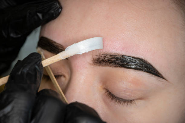 istock Removing eyebrows with hot wax. Cosmetician undergoing waxing procedure for human brow 1322499440