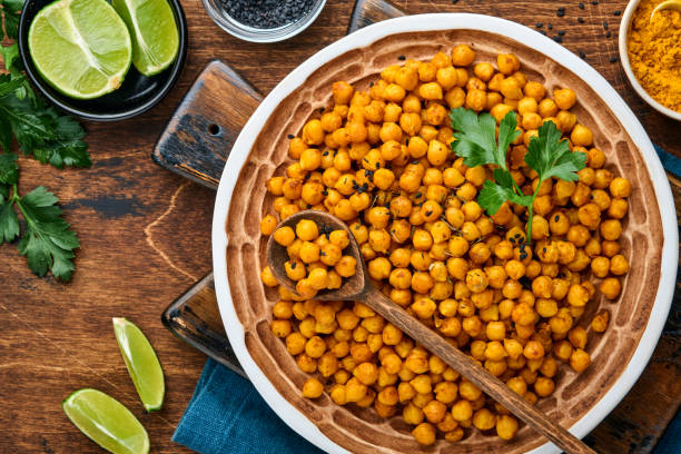 istock Fried chickpeas with turmeric in ceramic plate on an old wooden table background. Roasted spicy chickpeas or Indian chana or chole, popular snack recipe. Top view. 1322499616