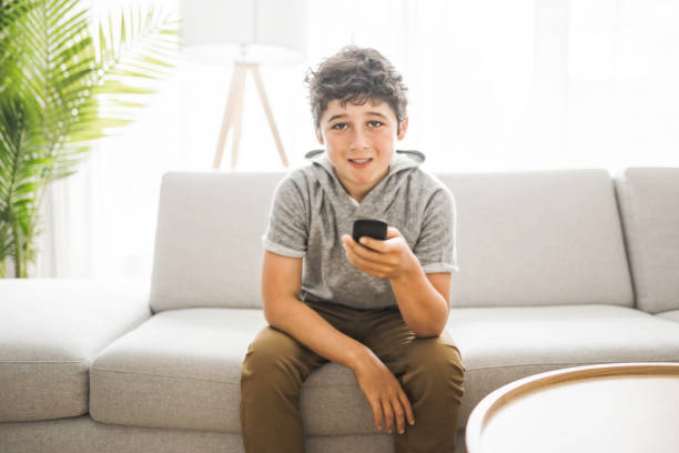 istock Young teen sitting on the couch using a remote control 1322501274