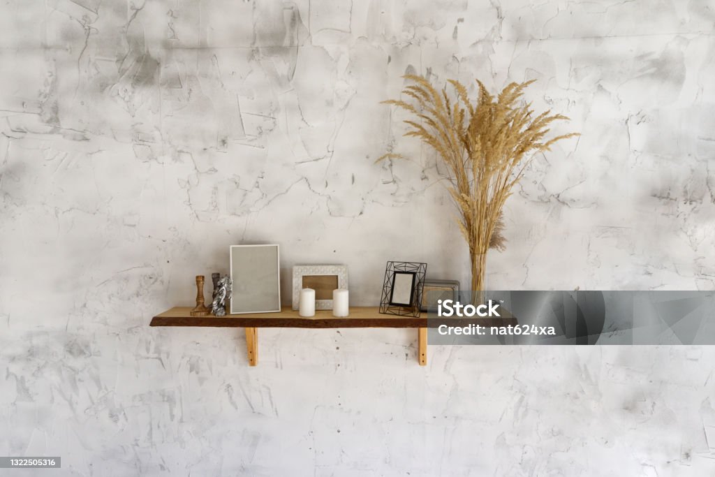 White eco style wall with a shelf and pampas grass, candles and photo frames decoration Apartment Stock Photo