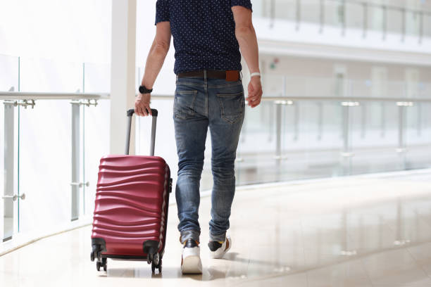 istock Man is rolling suitcase in hotel corridor 1322506713