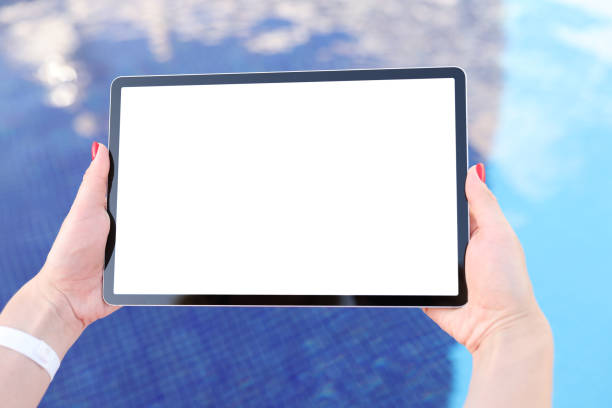 istock Female hands hold tablet with blank white screen above pool water 1322506720