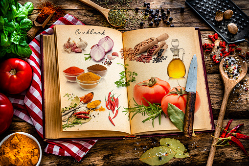 Open vintage cookbook with ingredients printed on it shot on rustic wooden table.