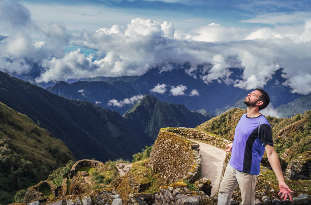 A man enjoying the valley landscape on inca trail ruins stock photo