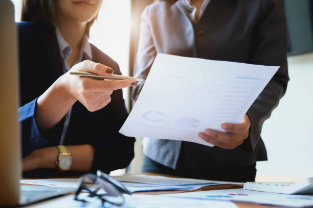 An auditor holds a pen pointing to documents to examine budgets and financial fraud stock photo