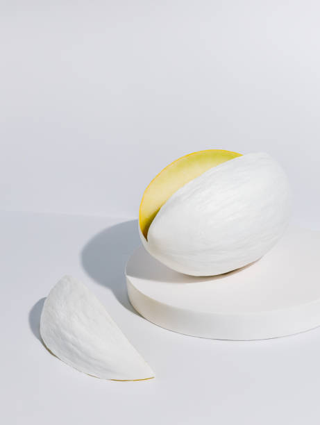 istock Mellon painted in white with a cut slice isolated on a white background. Honeydew melon vegetable placed on a monochrome matching podium. Creative health food concept. 1322511328