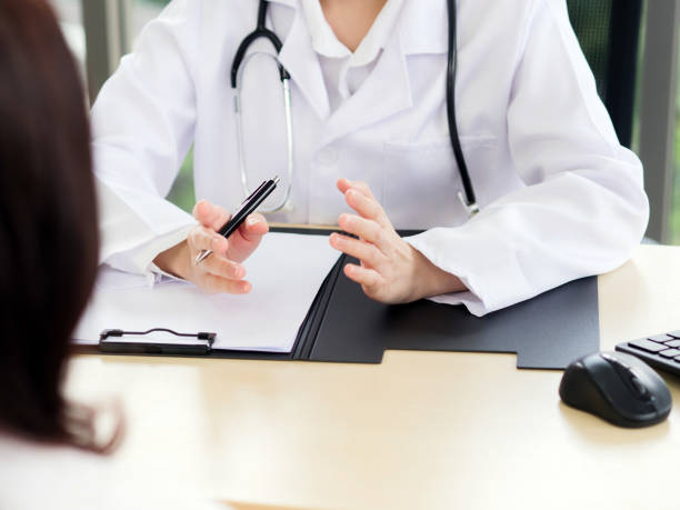 A close-up of the hand of a female doctor or nurse holding a pen is talking or explaining information or something for a patient. stock photo