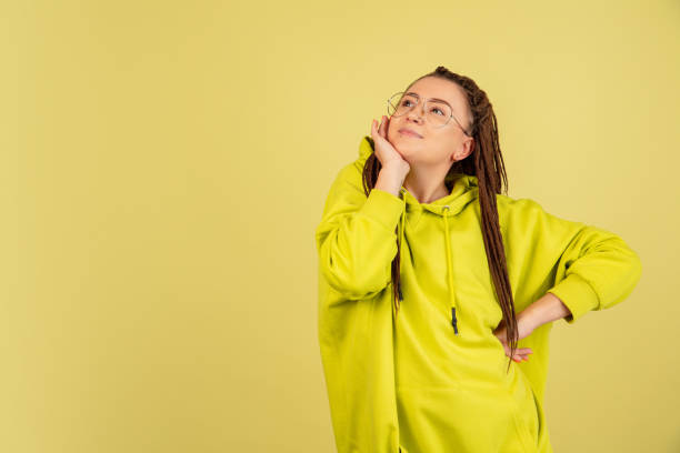 istock Cute model in yellow sweater over studio background with funny face. Thinking and wondering concepts. Lots of copy space for advertising 1322514497