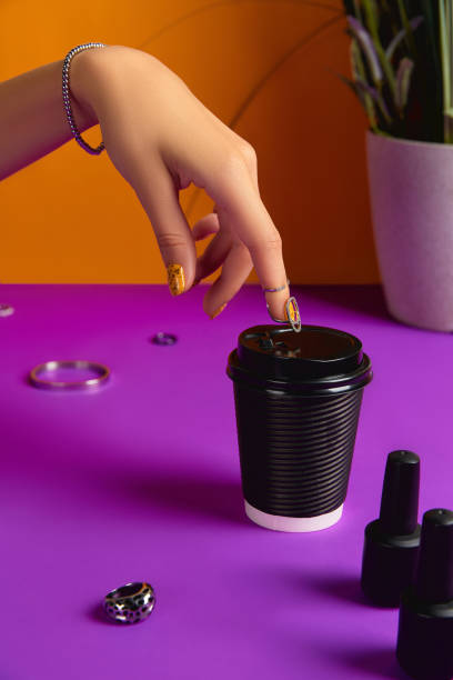 Womans hand with jewelry accessories, nail varnish bottle and paper cup over purple table Womans hand with jewelry accessories, nail varnish bottle and paper cup over purple table. Beauty fashion concept fall nail art stock pictures, royalty-free photos & images