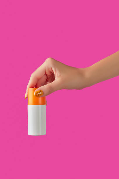 istock Manicured womans hand holding sunscreen bottle on pink background 1322516782