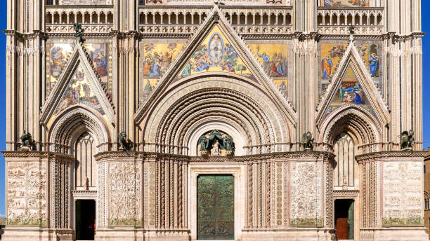 The splendid Gothic style facade of the Cathedral in the medieval town of Orvieto in Umbria central Italy A detailed front view of the stunning Gothic facade of the Basilica of Santa Maria Assunta or Duomo in the medieval town of Orvieto, in the Umbria region, central Italy. The construction of the magnificent Duomo, a masterpiece of Italian Gothic art, began in 1290 under the pontificate of Pope Nicholas IV and was completed in the second half of the 15th century. More than 20 artists worked on the magnificent façade of the Cathedral during the two centuries of construction of the church. With a population of just 20,000 people, Orvieto is considered one of the most beautiful cities of art in Italy, founded since the Etruscan and Roman times on the flat top of a large butte of volcanic tuff. This same material was used for the construction of almost all the medieval houses and churches of Orvieto, as well as its famous Gothic-style Cathedral. Image in high definition format. orvieto stock pictures, royalty-free photos & images