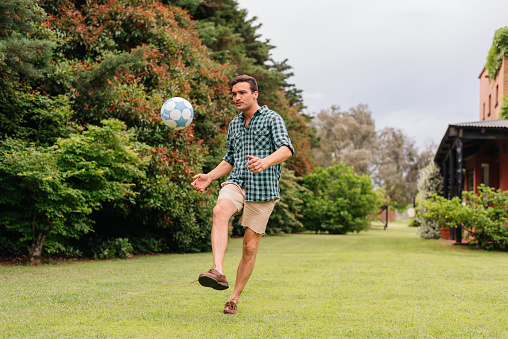 Man playing soccer on the backyard lawn.