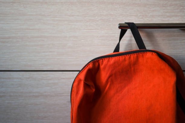 Bright orange school backpack hanging on the shelf