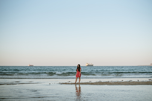 Young woman walking at the beach at sunset