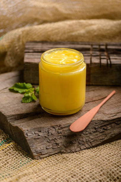 Ghee butter in glass jar with wooden spatula on wood. Ghee butter in glass jar with wooden spatula on wood. ghee stock pictures, royalty-free photos & images