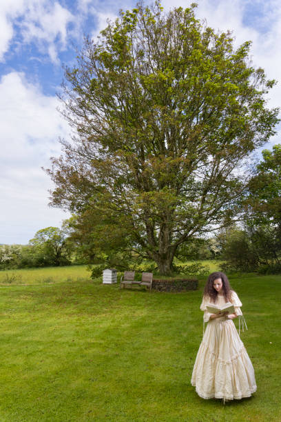 istock Victorian lady reading a book in her garden 1322532215