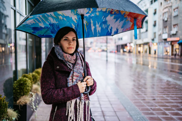 istock Woman walking downtown in rain 1322537380