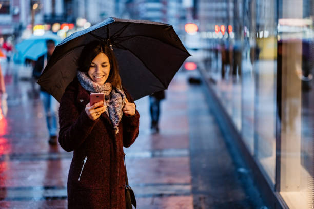 istock Woman using smartphone downtown in rain 1322537422