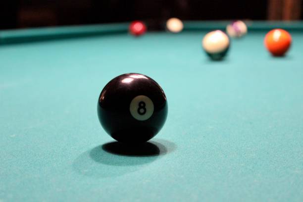 istock Black billiards ball with number 8 on a green billiard table. 1322539578