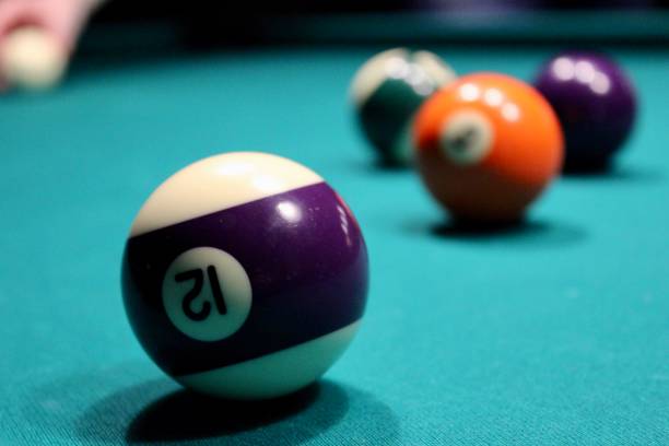 istock Black billiards ball with number 12 on a green billiard table. 1322539598