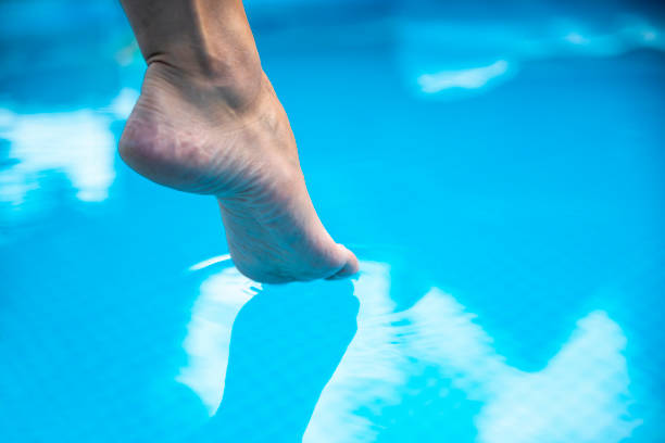 Closeup Caucasian Female foot entering the blue clear water
