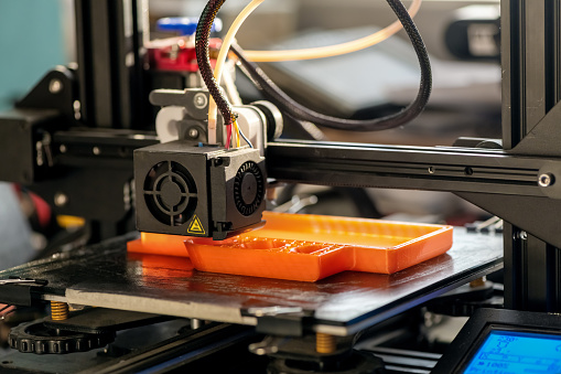 La impresora 3D imprime el modelo de plástico naranja photo