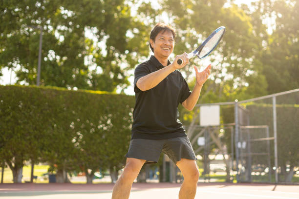 dojrzały filipiński mężczyzna grający w tenisa uderzający w zbliżenie piłki - tennis serving playing men zdjęcia i obrazy z banku zdjęć