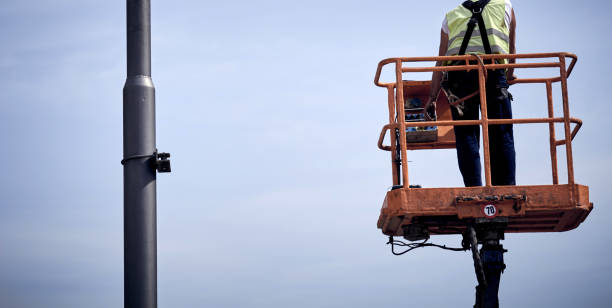istock Manual worker on a telescopic lifter basket fixing street light pole. 1322547676
