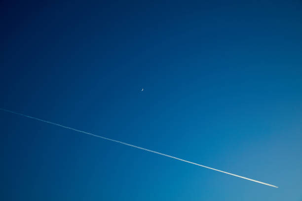 Moon and airplane on a blue darker sky. Moon and airplane on a blue darker sky. contrail moon on a night sky stock pictures, royalty-free photos & images