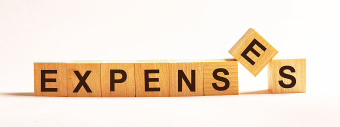 The word expenses made up of wooden cubes on a light background