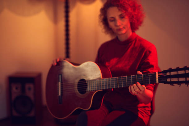 woman playing acoustic guitar in a retro vintage room. - fingerstyle imagens e fotografias de stock