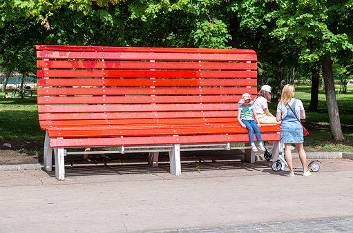 Samara, Russia - June 6, 2021: Big red bench for rest in a city park