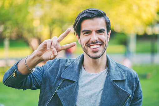 Young man showing the peace sign in the park