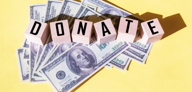 DONATE text on wooden cubes. Dollars lie on a yellow background
