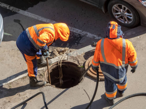 Workers over the open sewer hatch Workers over the open sewer hatch on a street. Repair of sewage, underground utilities, water supply system, water pipe accident manhole stock pictures, royalty-free photos & images