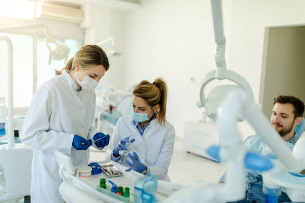 The female dentist and the assistant prepare the instruments for the dental examination. stock photo