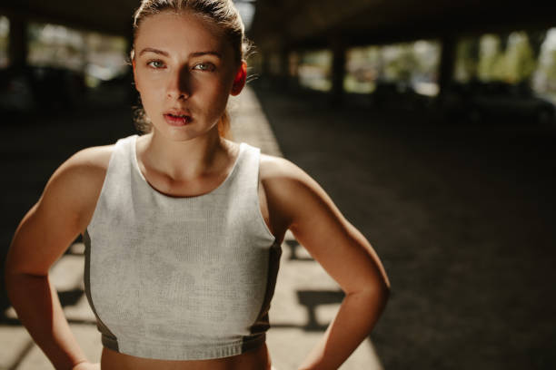 Close up photo of athletic blonde woman sweating taking a break from workout and looking at the camera.