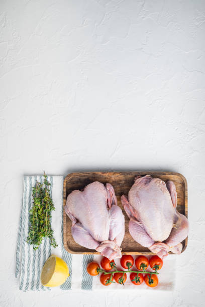 istock Whole raw free range chicken with herbs and ingredients, on white background, top view with copy space for text 1322557346