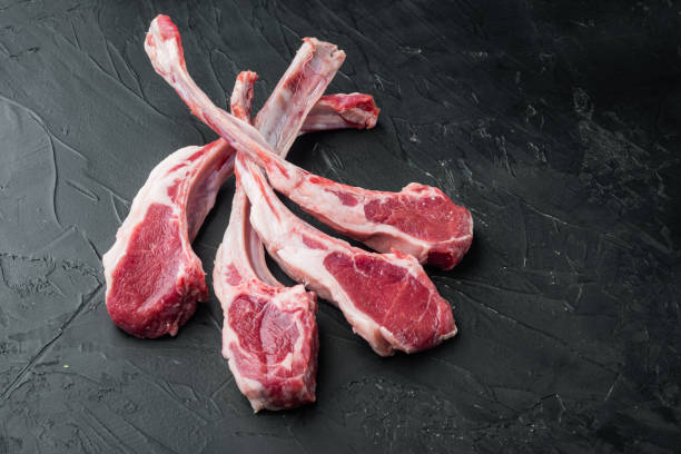 生のラムチョップまたは羊肉のカット、黒い石の背景に、コピースペースとテキスト用のスペース - rack of lamb chop raw meat ストックフォトと画像